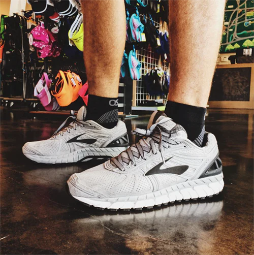 Man in sneakers wearing black OS1st FS4 Quarter Crew Socks designed for Plantar Fasciitis relief, providing targeted compression and support for the arch and heel of the foot.