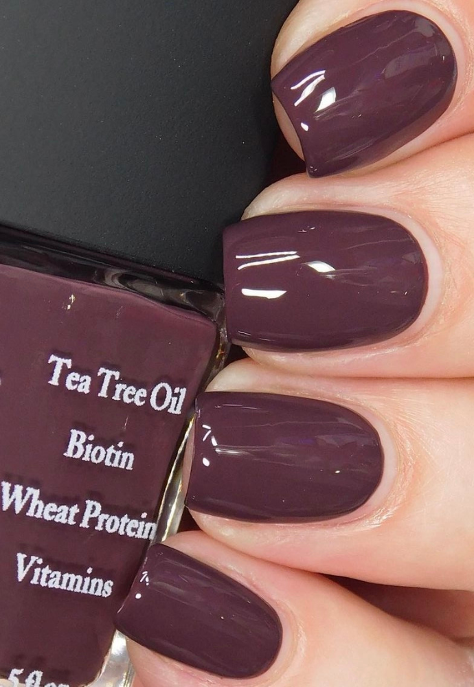 Beautiful nails holding Dr.'s Remedy Enriched Nail Polish in DESIRE Dark Brown, a richly pigmented, milk chocolate dipped plum shade enriched with Tea Tree Oil, Biotin, and Wheat Protein for healthy nails