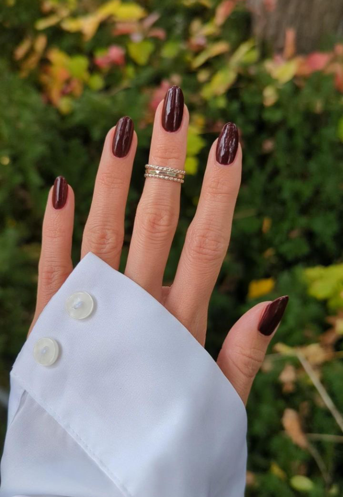 Beautiful nails painted with Dr.'s Remedy Enriched Nail Polish in MEANINGFUL Merlot, a blend of deep purple and red wine burgundy infused with dark berries, showcasing a glossy finish and complemented by gold rings