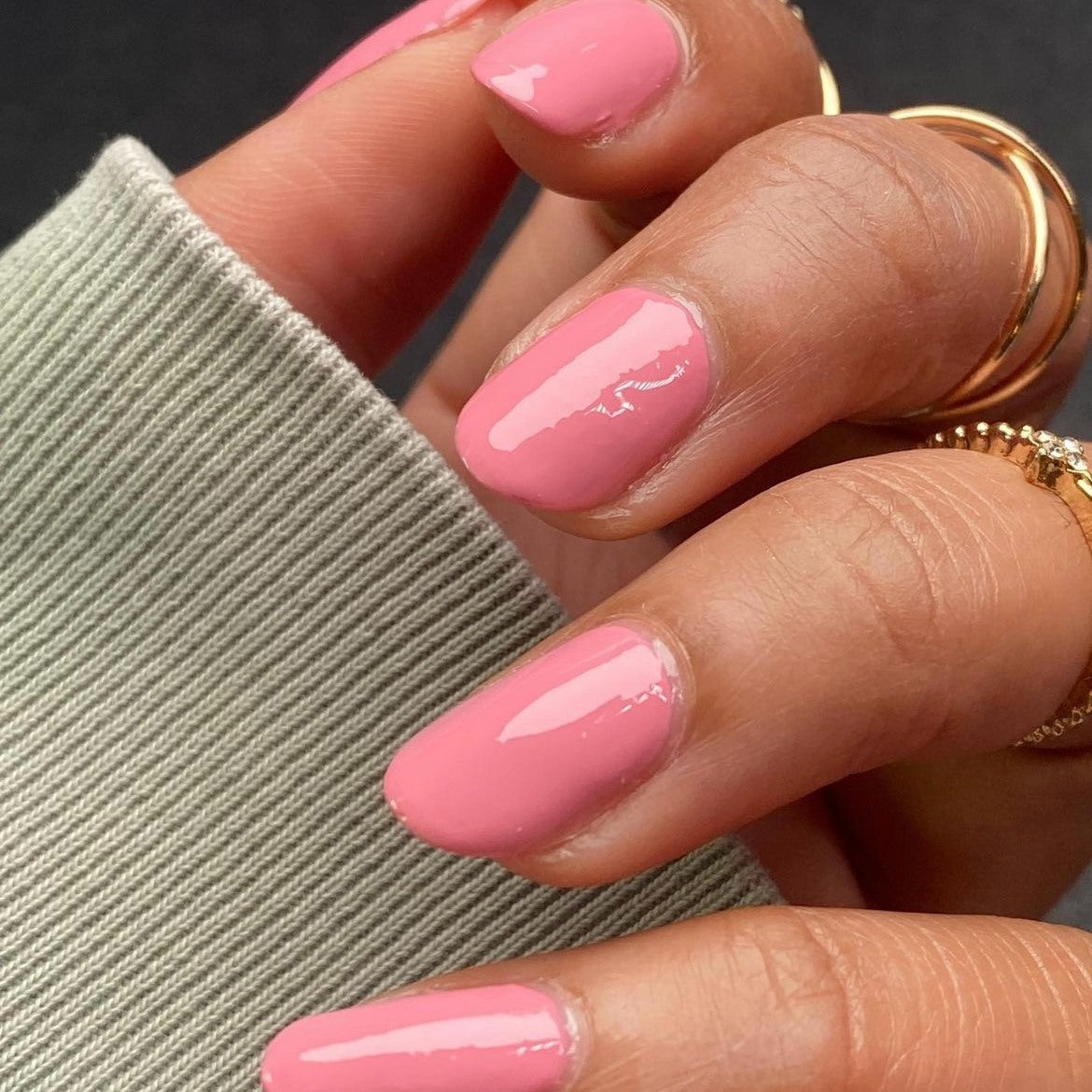 Beautiful nails painted with Dr.'s Remedy Enriched Nail Polish in POSITIVE pink, a baby girl pink with swirls of pale purple, showcasing a glossy finish and complemented by gold rings