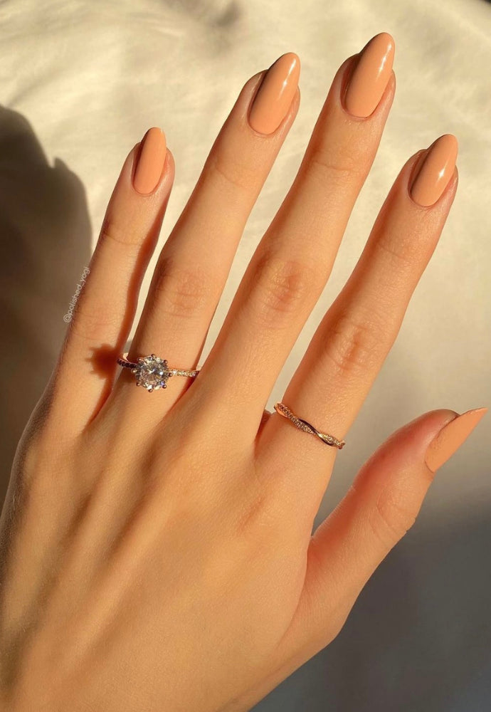 Beautiful nails painted with Dr.'s Remedy Enriched Nail Polish in POLISHED Pale Peach, a velvety pinky-peach shade, showcasing a glossy finish and complemented by diamond rings