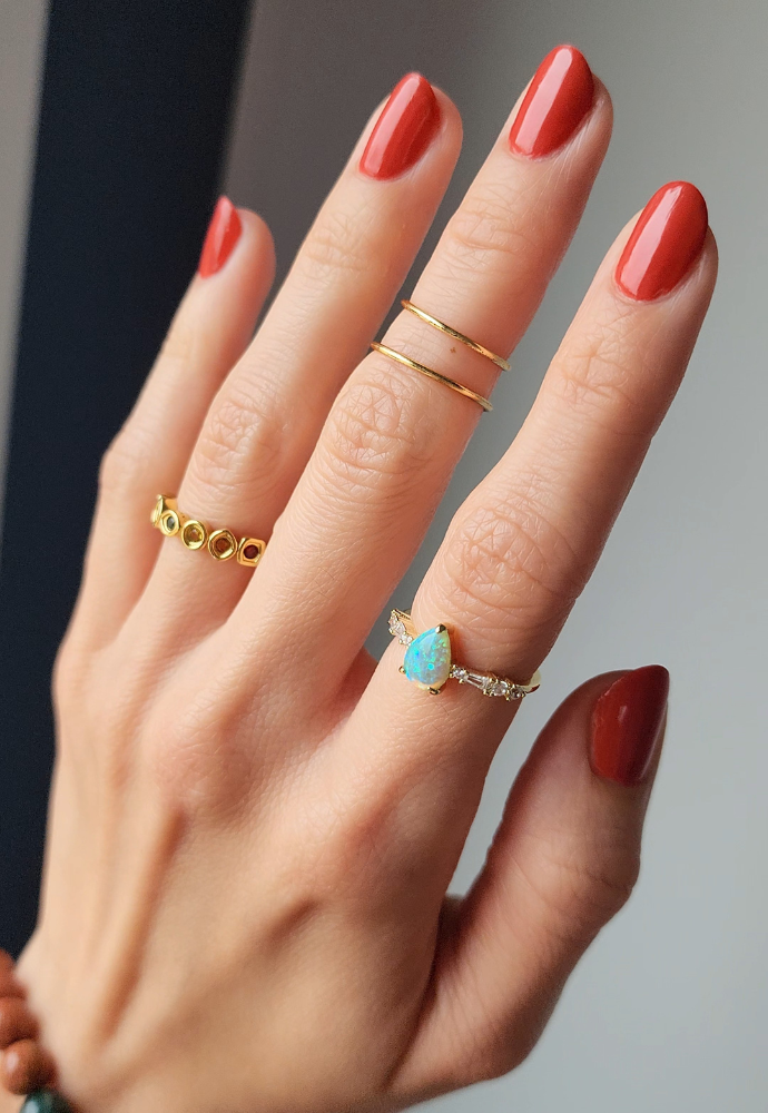 Beautiful nails painted with Dr.'s Remedy Enriched Nail Polish in ALTRUISTIC Auburn, a rich burnt orange shade, showcasing a glossy finish and complemented by gold rings