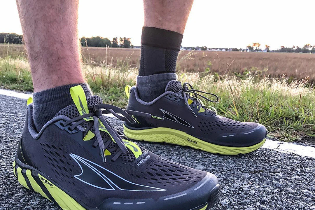 Men's legs in sneakers wearing OS1st AF7 Ankle Bracing Sleeve in black under socks, providing targeted compression and support to relieve ankle pain and instability, designed to improve mobility and enhance performance.