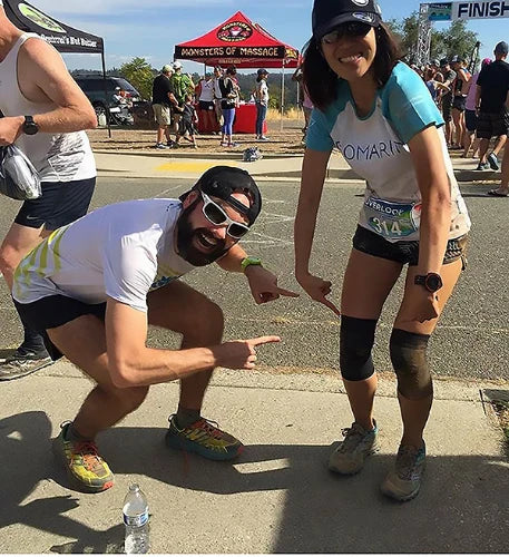 Marathon runner wearing two OS1st KS7 Performance Knee Sleeves in black, offering targeted compression to support knee pain relief, improve mobility, and enhance performance during physical activity.