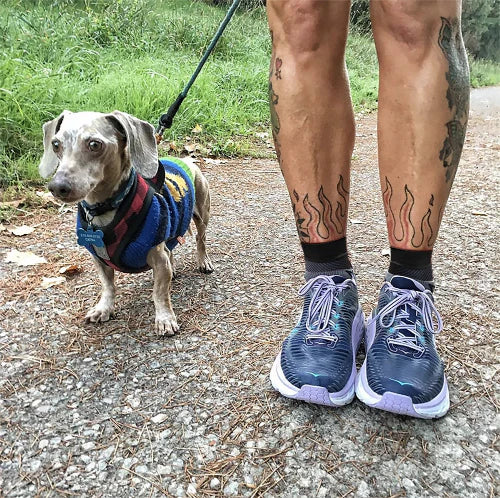 Person wearing sneakers and FS6 Compression Foot Sleeves walking a small dog