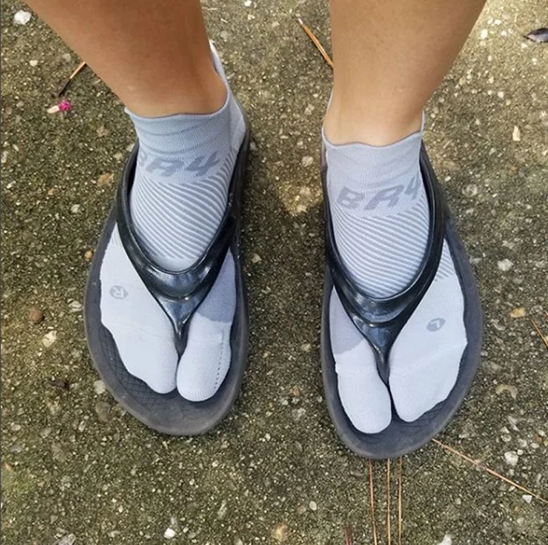 Person in flip flops wearing OS1st BR4 Bunion Relief Socks, designed with targeted compression to alleviate bunion pain and provide comfort and support for improved mobility.