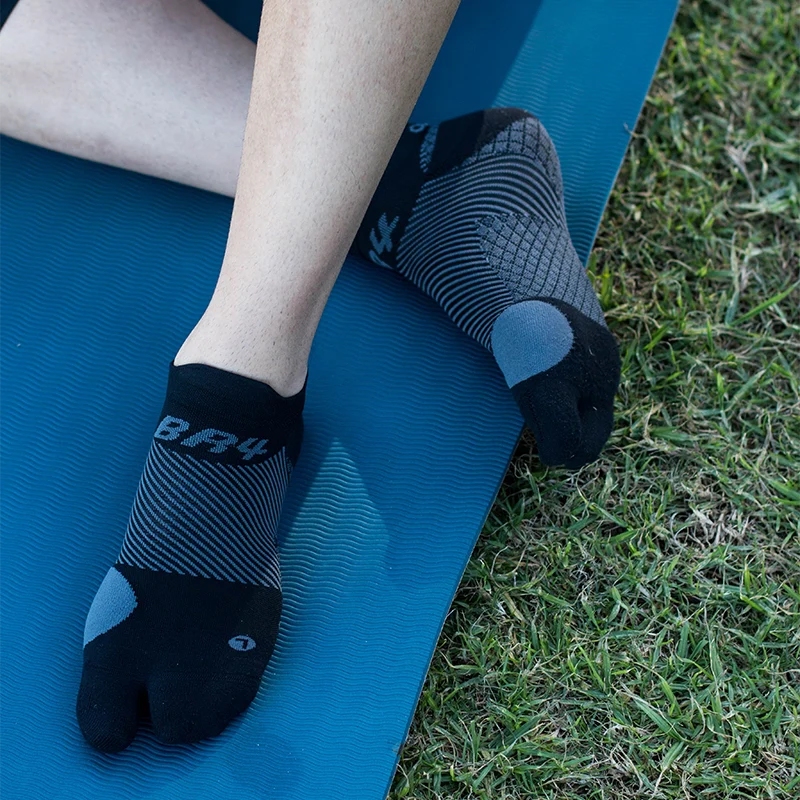 Person sitting on yoga mat on grass wearing OS1st BR4 Bunion Relief Socks, designed with targeted compression to alleviate bunion pain and provide comfort and support for improved mobility.