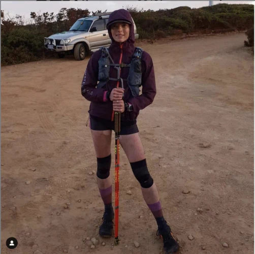 Hiker standing wearing two OS1st KS7 Performance Knee Sleeves in black, offering targeted compression to support knee pain relief, improve mobility, and enhance performance during physical activity.