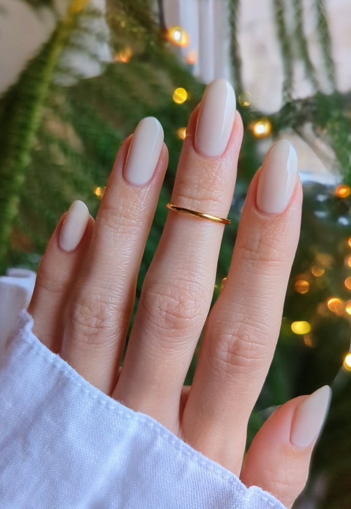 Beautiful nails painted with Dr.'s Remedy Enriched Nail Polish in LOYAL Linen, a sheer, ivory nude shade, showcasing a glossy finish and complemented by a gold ring