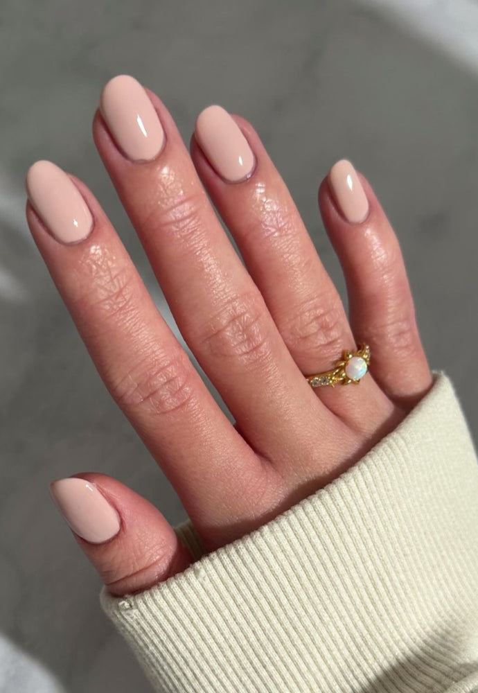 Beautiful nails painted with Dr.'s Remedy Enriched Nail Polish in PRECIOUS Pink, a soft, subtle cotton candy like hue with purple reflections, showcasing a glossy finish and complemented by gold rings