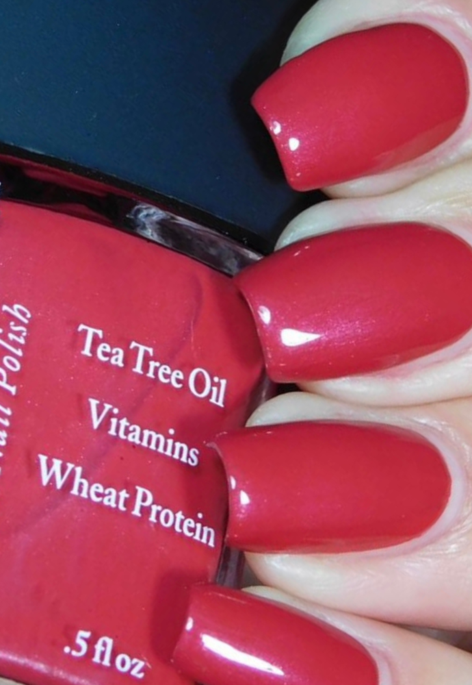 Beautiful nails holding Dr.'s Remedy Enriched Nail Polish in CHEERFUL Cherry, a bold, juicy and upbeat shimmer-flecked candy apple red shade enriched with Tea Tree Oil, Biotin, and Wheat Protein for healthy nails