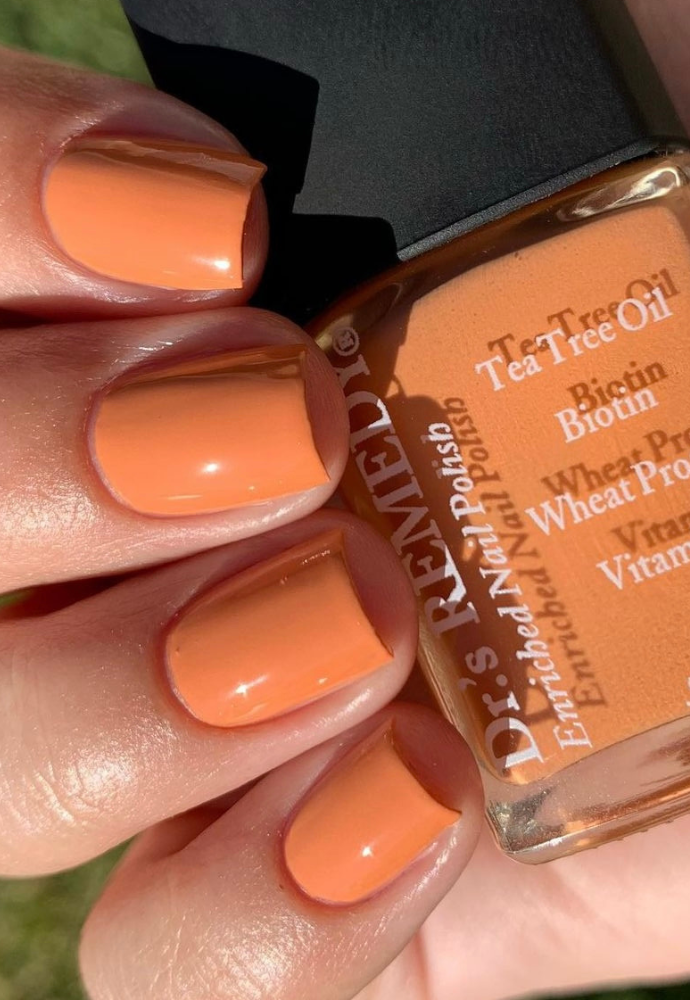 Beautiful nails holding Dr.'s Remedy Enriched Nail Polish in AUTHENTIC Apricot, a creamiscle-like orange shade enriched with Tea Tree Oil, Biotin, and Wheat Protein for healthy nails