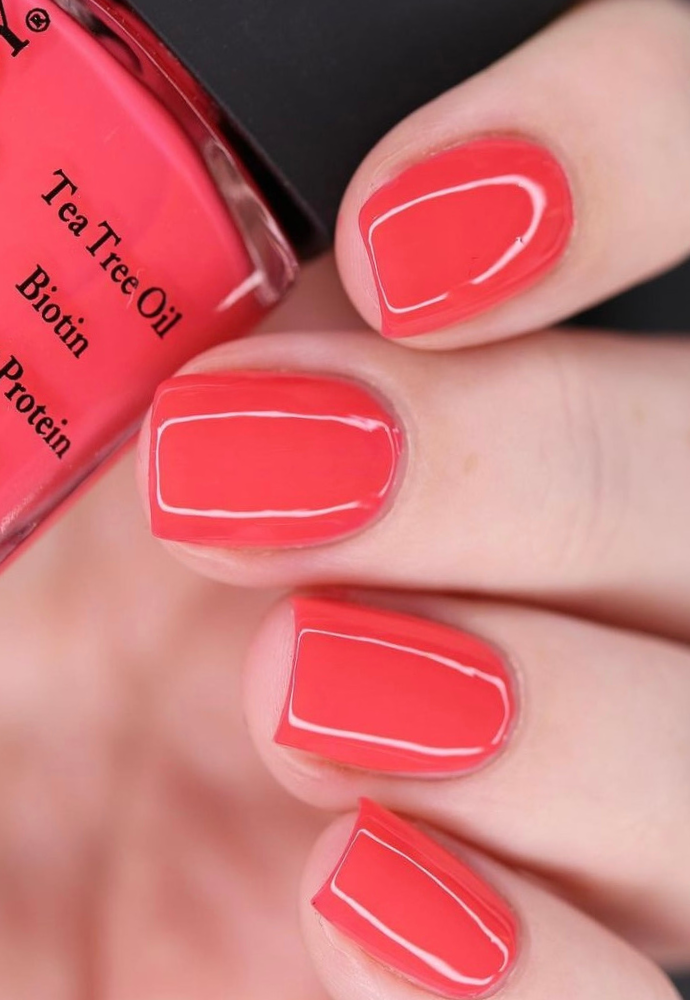 Beautiful nails holding Dr.'s Remedy Enriched Nail Polish in PEACEFUL Pink Coral, a bright pink coral shade enriched with Tea Tree Oil, Biotin, and Wheat Protein for healthy nails